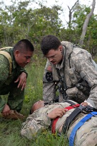 U.S. Army Staff Sgt. Zach Lattimore, 1-228 Aviation Regiment flight medic, treats a simulated patient alongside a Belize Defense Force member during a mock medical evacuation mission Oct. 26, 2015, in Belize. The training prepared the teams for any potential scenario that may have required a medical evacuation during a four-day drug eradication operation. (U.S. Air Force photo by Senior Airman Westin Warburton/Released)