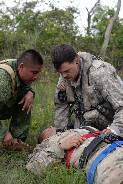 U.S. Army Staff Sgt. Zach Lattimore, 1-228 Aviation Regiment flight medic, treats a simulated patient alongside a Belize Defense Force member during a mock medical evacuation mission Oct. 26, 2015, in Belize. The training prepared the teams for any potential scenario that may have required a medical evacuation during a four-day drug eradication operation. (U.S. Air Force photo by Senior Airman Westin Warburton/Released)
