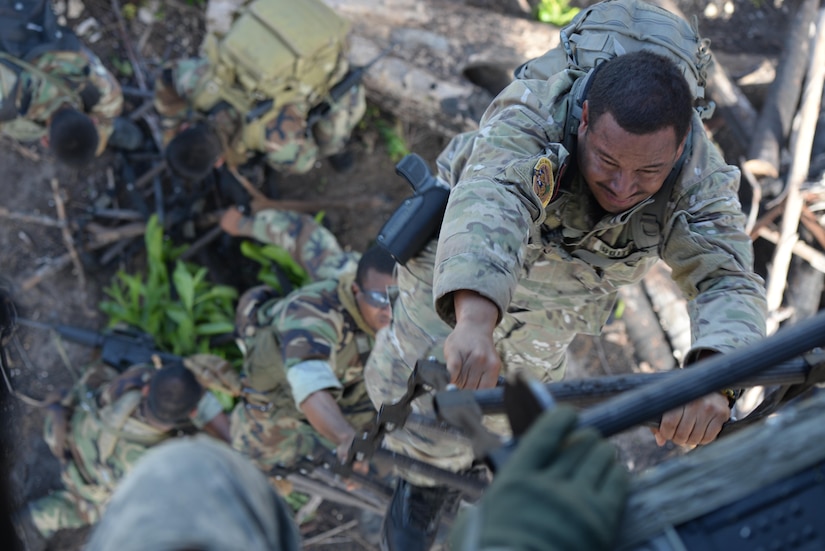 Belizean security forces members climb a ladder to board a U.S. Army CH-47 Chinook helicopter providing airlift support during a marijuana eradication mission,Oct. 27, 2015 in Belize. The Belizean security forces and U.S. Army operated together during the four-day mission to destroy over 50,000 marijuana plants used in drug trafficking in Central America. (U.S. Air Force photo by Senior Airman Westin Warburton/Released)