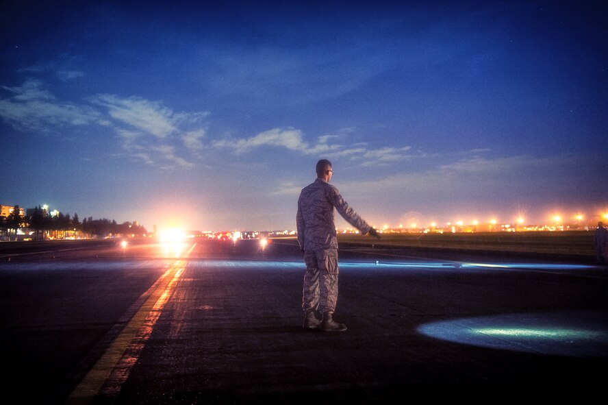 Senior Airman Brandon Miller, 374th Civil Engineer Squadron electrical power production journeyman, guides portable aircraft arresting system engine operators at Yokota Air Base, Japan, Nov. 6, 2015. The AAS is designed to safely bring aircraft to a stop in the event of an emergency. (U.S. Air Force photo by Airman 1st Class Delano Scott/Released)