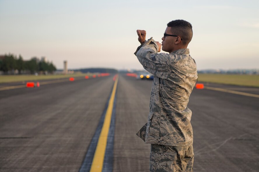 Senior Airman Brandon Miller, 374th CES electrical power production journeyman, gives a signal to a portable aircraft arresting system engine operator at Yokota Air Base, Japan, Nov. 6, 2015. Aircraft arresting systems are used to rapidly decelerate an aircraft as it lands. (U.S. Air Force photo by Airman 1st Class Delano Scott/Released)