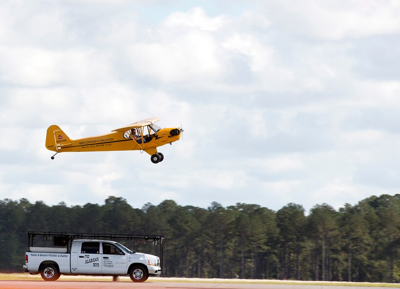 Greg Koontz, Alabama Boys Piper J-3 Cub pilot, attempts to land on a moving vehicle during the Thunder Over South Georgia Nov. 7, 2015, at Moody Air Force Base, Ga. During the performance, Koontz acts as Clem Cleaver, who steals a plane and is forced to successfully land the aircraft on a moving pick-up truck after its tire is shot out. (U.S. Air Force photo by Airman 1st Class Greg Nash/Released) 