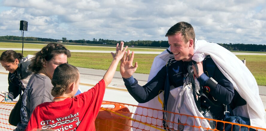 A member of the United Stated Air Force Academy Wings of Blue greets a visitor after parachuting during the Thunder Over South Georgia Nov. 7, 2015, at Moody Air Force Base, Ga. Wings of Blue runs the parachuting course known as Airmanship 490 (AM-490) which is the only certified first-jump program in the world where students can make unassisted jumps. (U.S. Air Force photo by Airman 1st Class Greg Nash/Released) 