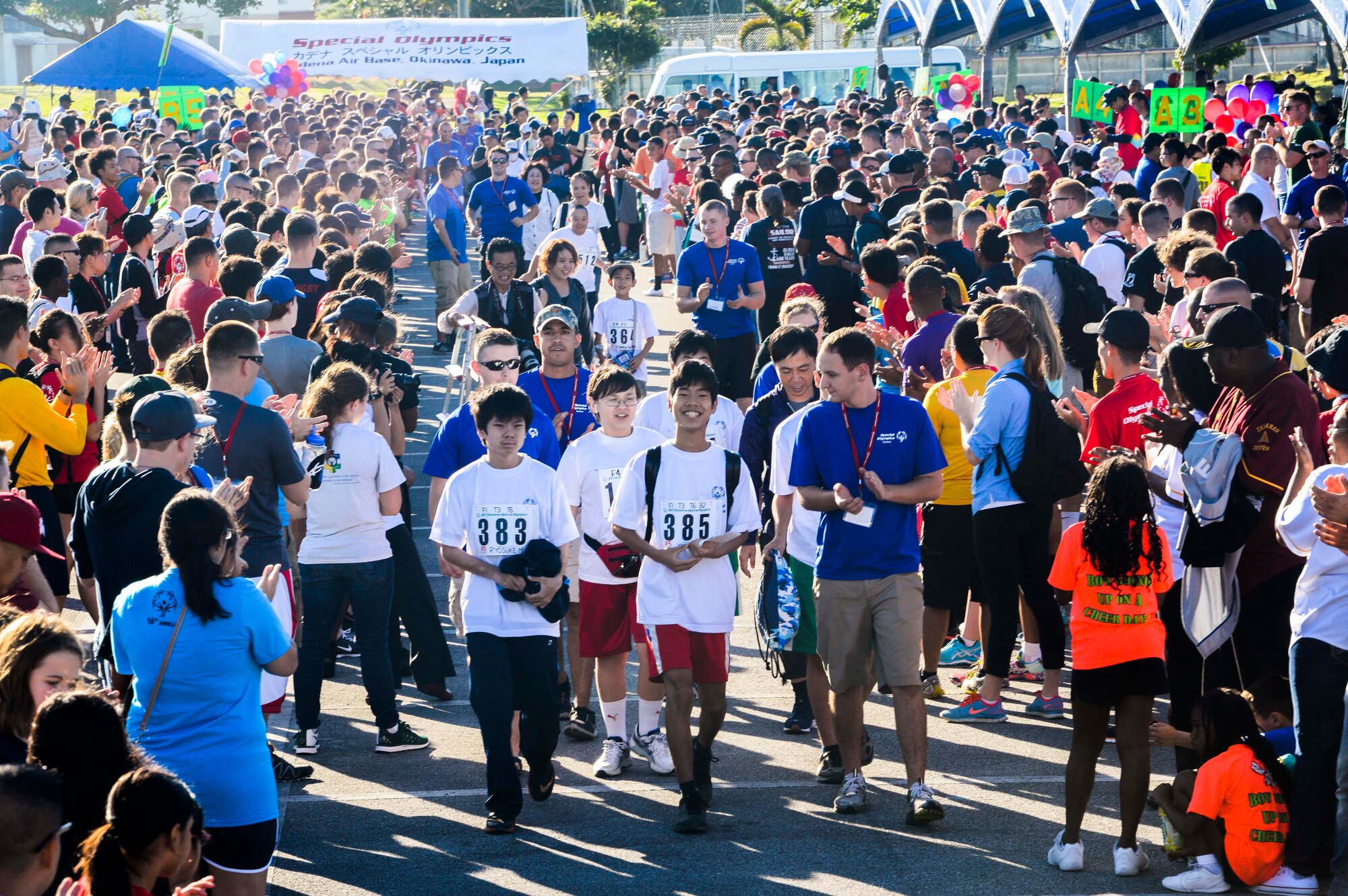 Hundreds of volunteers and spectators of the Kadena Special Olympics form a human pathway to greet and cheer on arriving athletes as they are shuttled to the Risner Fitness Center Sports Complex Nov. 7, 2015, at Kadena Air Base, Japan. Thousands of spectators from Japan and the U.S. came out to support approximately 880 athletes and artists participating in the 16th annual KSO games and art show. (U.S. Air Force photo by Senior Airman John Linzmeier) 