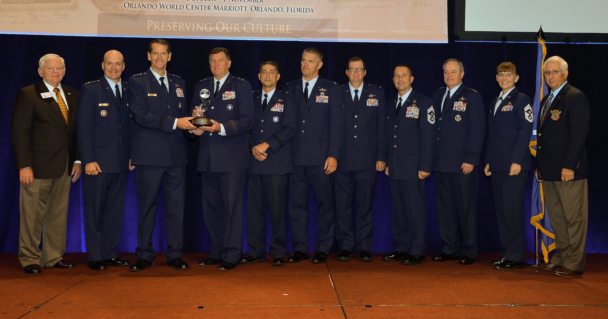 The director of the Air National Guard, Lt. Gen. Stanley Clarke III (third from left) presents Maj. Gen. Edward Tonini (fourth from left), adjutant general of the Commonwealth of Kentucky, with the 2015 Airlift/Tanker Association’s Major General Stanley F.H. Newman Outstanding Unit Award during the annual A/TA Convention in Orlando, Fla., Oct. 30, 2015. The award was bestowed this year on the Kentucky Air National Guard’s 123rd Airlift Wing, based in Louisville, for exceptional performance from July 1, 2014 to June 30, 2015. Also pictured (left to eight) are Gen. Arthur Lichte (retired), chairman of the A/TA; Gen. Carlton Everhart II, commander of Air Mobility Command; Brig. Gen. Warren Hurst, Kentucky’s assistant adjutant general for Air; Col. Barry Gorter, commander of the 123rd Airlift Wing; Col. Robert Hamm, commander of the 123rd Operations Group; Chief Master Sgt. Ray Dawson, command chief of the 123rd Airlift Wing; Gen. Mark Welsh III, chief of staff of the U.S. Air Force; Chief Master Sgt. Victoria Gamble, command chief of Air Mobility Command; and Lt. Gen. Christopher Kelly (retired), former vice commander of Air Mobility Command. (U.S. Air Force photo).