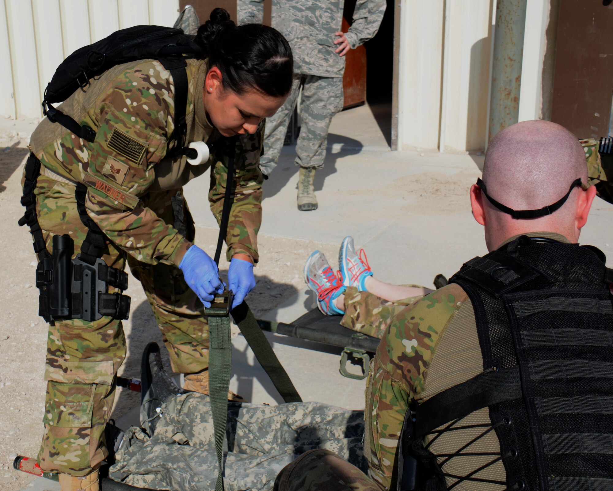 Tech. Sgt. Patricia Wagner, 379th Expeditionary Medical Group respiratory therapist, secures a litter strap outside the 379th Expeditionary Aeromedical Evacuation Squadron’s warehouse during a mass casualty exercise at Al Udeid Air Base, Qatar Nov. 6. The exercise provided medical teams with an opportunity to provide care for patients in a mass-casualty situation. Teams were evaluated on set up, patient movement and communication. (U.S. Air Force photo by Tech. Sgt. James Hodgman)