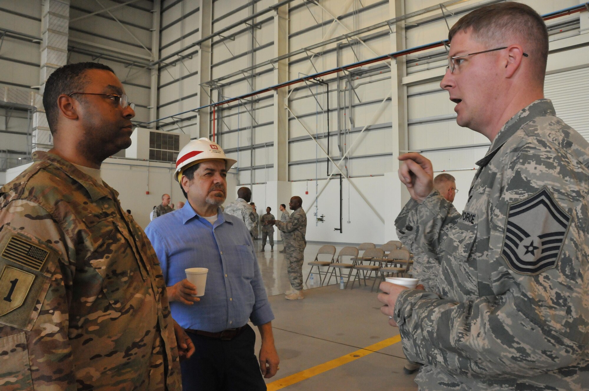 Senior Master Sgt. Aaron Gilbert, 379th Expeditionary Maintenance Squadron accessories flight chief, talks with Lt. Col. Claude A. Wilson, U.S. Army Corps of Engineers officer-in-charge, while attending a ribbon cutting ceremony for the multi-use hangar at Al Udeid Air Base, Qatar Nov. 6.  The hangar will allow aircraft deployed to AUAB to be serviced in an area free from weather conditions. (U.S. Air Force photo by Tech. Sgt. Terrica Y. Jones/Released)