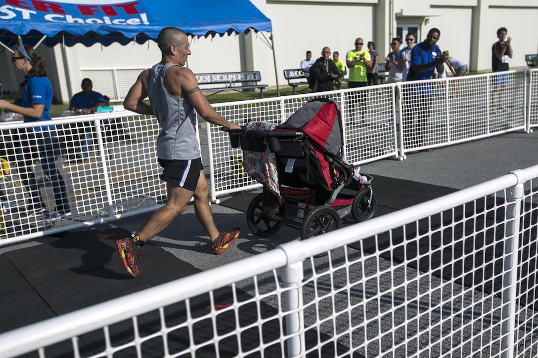 A runner crosses the finish with his children in tow during the Habu Fun Run Oct. 26 on Marine Corps Air Station Futenma, Okinawa, Japan. Runners chose one of two paths at the beginning of their cardiovascular journey, either a five kilometer or 10 kilometer course.