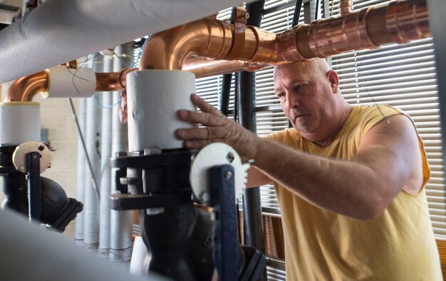 A workman from BASCO Group, the contractor for the boiler replacement project, installs insulation onto the pipes of the new boiler in building 672, Oct. 15. During energy action month, new high-efficiency boilers were installed in some of the buildings at Vance. (U.S. Air Force/ Staff Sgt. Nancy Falcon)