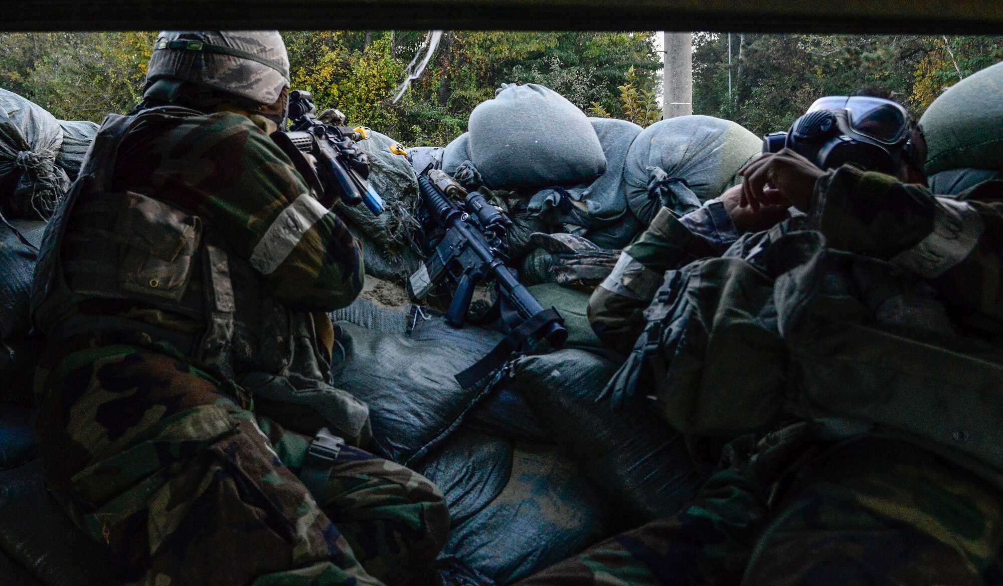 Airman 1st Class John Contreras, (left), 51st Security Forces Squadron, watches for opposing forces while Airman 1st Class Marlon Alcampor, 51st SFS, puts on protective gear during an attack by opposing forces as part of readiness exercise Vigilant Ace 16 on Osan Air Base, Republic of Korea, Nov. 4, 2015. During the week, defenders showcased their ability to position, employ and sustain forces during a variety of simulated attacks. The exercise allowed defenders to train in mission oriented protective posture, or MOPP, gear along with actively role-playing with simulated opposing forces (U.S. Air Force photo/Senior Airman Kristin High)