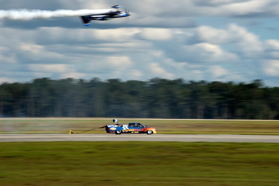 Rob Holland flies in an MXS aircraft over the Flash Fire Jet truck during the Thunder Over South Georgia Open House Nov. 7, 2015, at Moody Air Force Base, Ga. The truck can reach speeds up to 400 mph. (U.S. Air Force photo by Staff Sgt. Eric Summers Jr./Released)