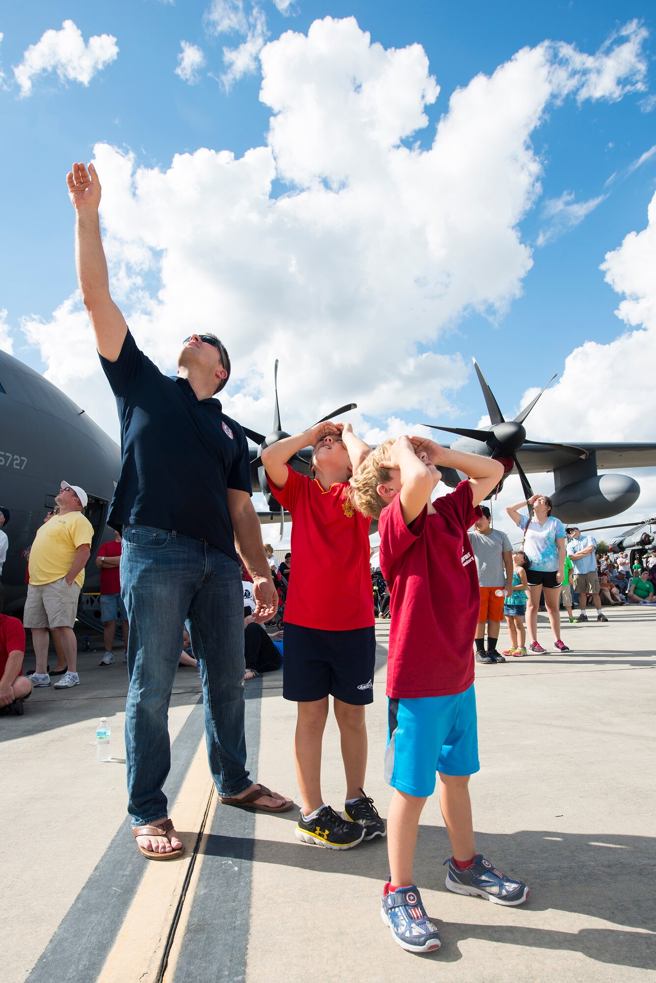 U.S. Air Force Master Sgt. Gregory Mitchell and his two sons, Gavin and Logan, attempt to locate an aircraft flying overhead during the Thunder Over South Georgia Open House, Nov. 7, 2015, at Moody Air Force Base, Ga. The Mitchell family recently arrived in the local community just in time to attend open house weekend. (U.S. Air Force photo by Senior Airman Ceaira Tinsley/Released)