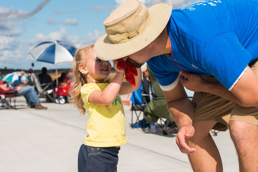 Isla, daughter of Lamar and Tacey Williams, uses a wet towel to wipe her father’s face during the Thunder Over South Georgia Open House, Nov. 7, 2015, at Moody Air Force Base, Ga. Guests in attendance found creative ways to stay cool by using wet towels, umbrellas and sitting underneath shaded areas. (U.S. Air Force photo by Senior Airman Ceaira Tinsley/Released)