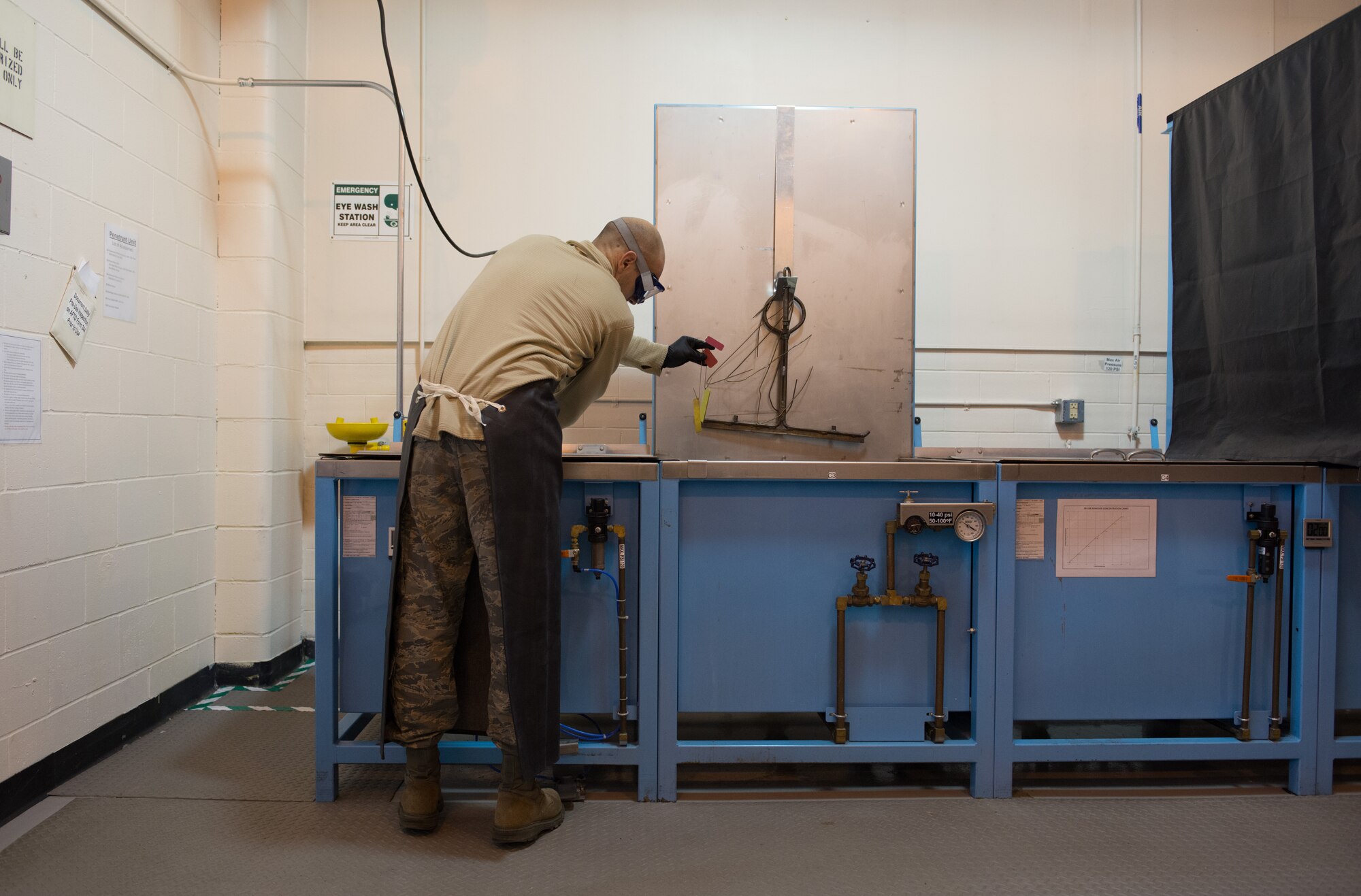 Staff Sgt. Ryan Bauman removes two cracked chrome panels from a vat of liquid penetrant on Nov. 7. (U.S. Air Force photo by Staff Sgt. Trevor Saylor)