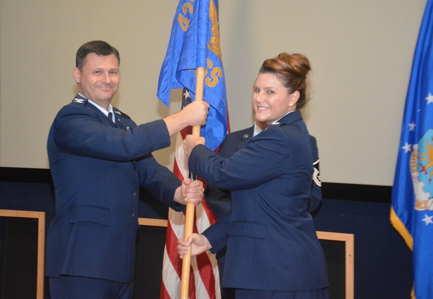 Col. Lee Merkle, 433rd Operations Group commander, passes the 433rd Operations Support Squadron guidon to the new squadron commander, Lt. Col. Kari Hill, during an assumption of command ceremony at Joint Base San Antonio-Lackland Nov. 7, 2015. Before taking on her present role, Hill served as a C-5 pilot assigned to the 68th Airlift Squadron here at Lackland. (U.S. Air Force photo/Senior Airman Bryan Swink)