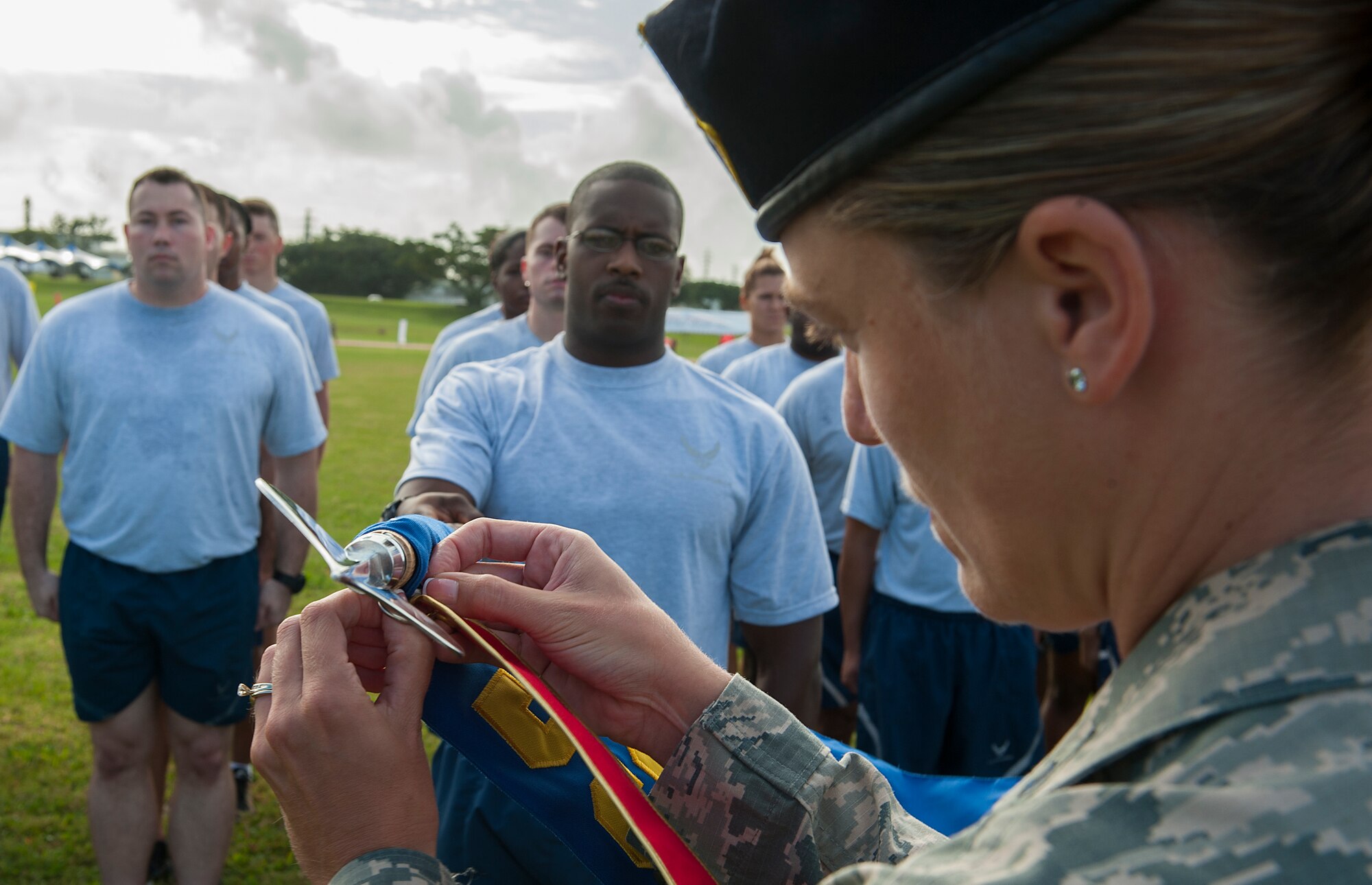 U.S. Air Force Lt. Col. Sarah Babbitt, 18th Security Forces Squadron commander, pins the Kadena Special Olympics Torch Run ribbon on the 18th Wing guide-on, carried by Tech. Sgt. Marquis Taylor, 18th SFS anti-terrorism specialist, Nov. 6, 2015, at Kadena Air Base, Japan. The KSO Torch Run kicked off the 2015 KSO, the largest Special Olympics event outside the United States. (U.S. Air Force photo by Airman 1st Class Corey M. Pettis)