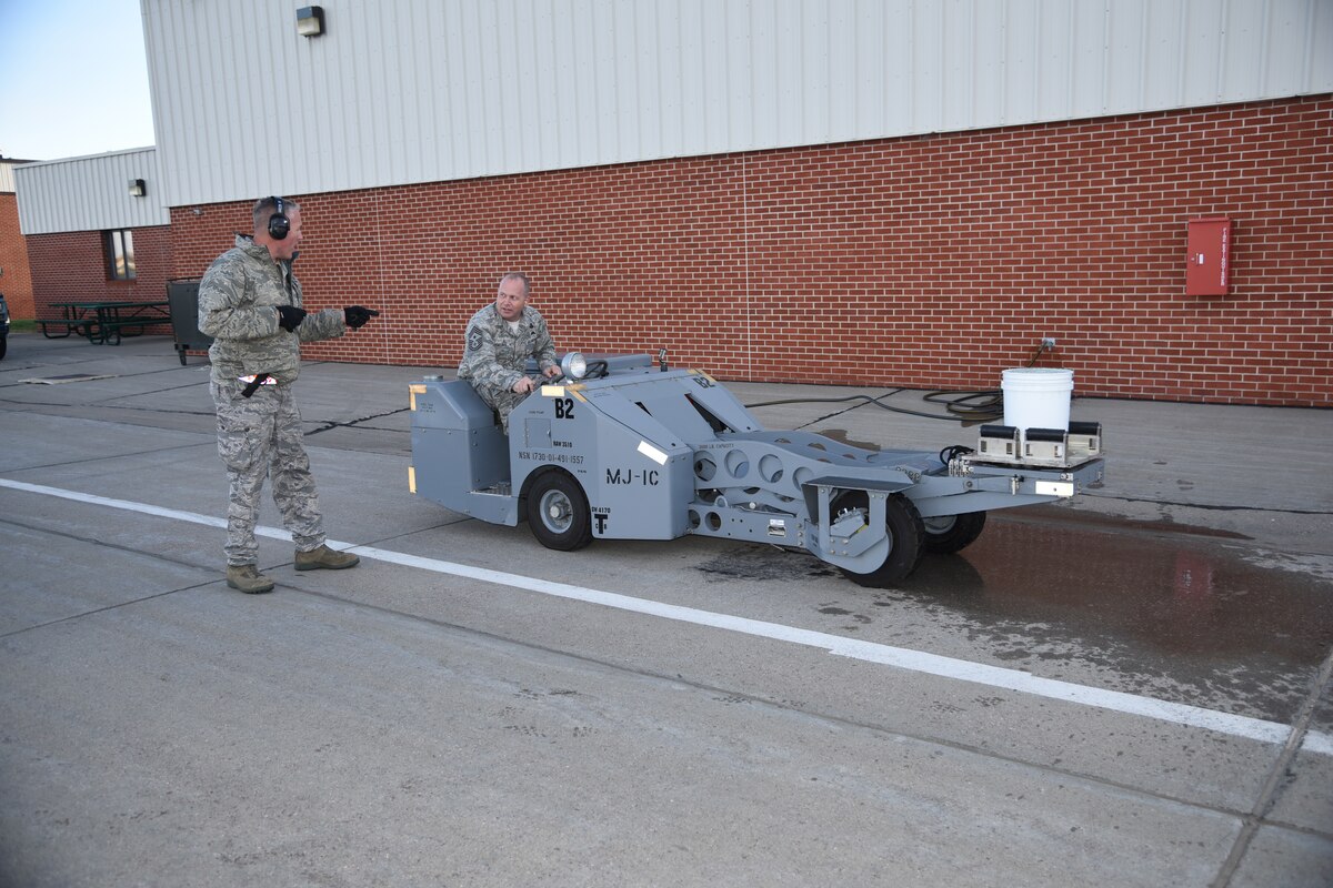 SIOUX FALLS, S.D. - Command Chief Master Sergeant of the Air National Guard James W. Hotaling listens as Master Sgt. Steven Rowe, 114th Maintenance Group armament systems specialist, gives him instructions on the “Chief’s Challenge” he participated in at the 114th Fighter Wing Nov. 6, 2015.  Hotaling completed an MJ-1 Jammer driving challenge maneuvering the vehicle around cones and obstacles with a bucket full of water to gauge his accuracy. (U.S. Air National Guard photo by Senior Master Sgt. Nancy Ausland/Released)