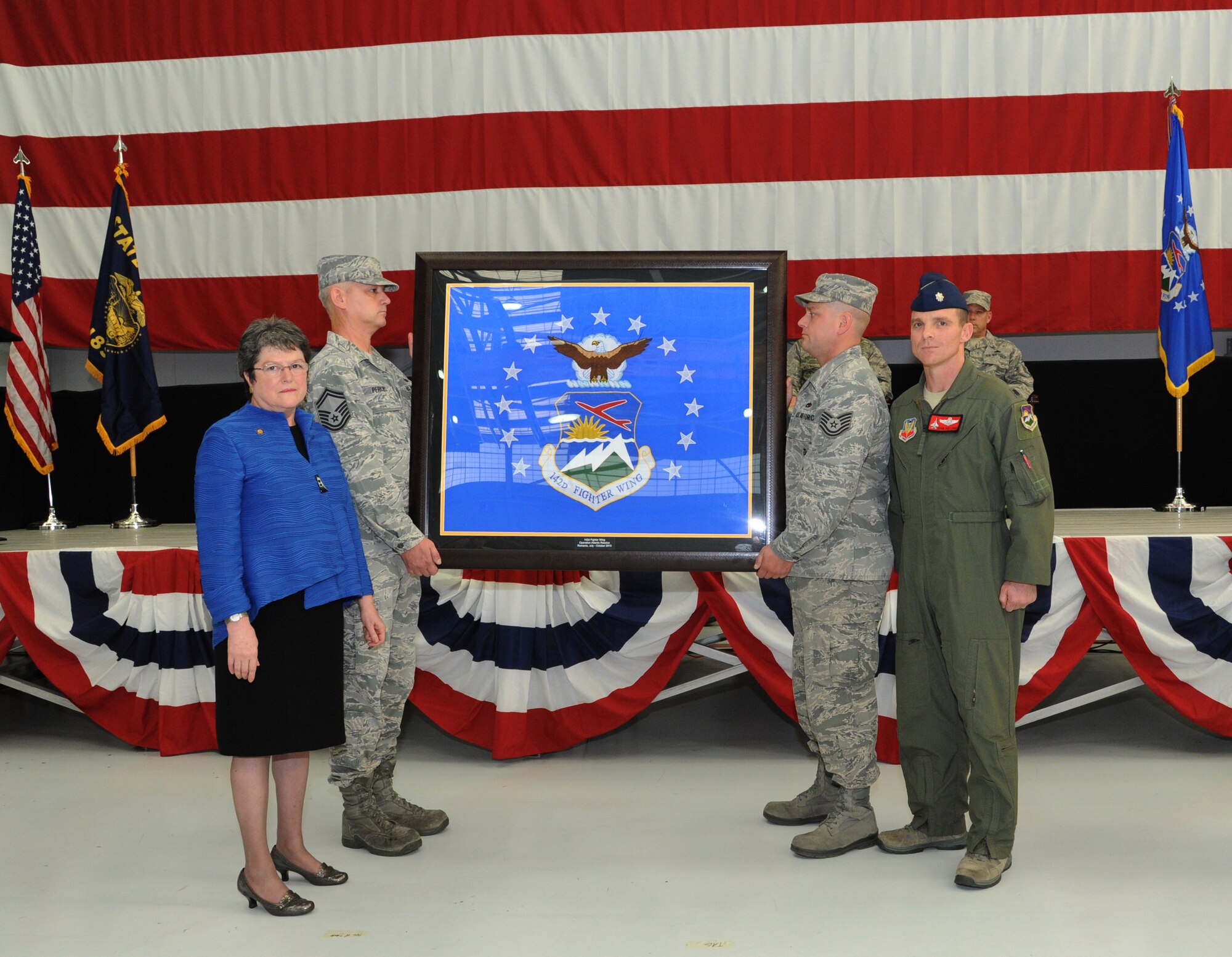 Oregon Secretary of State Jeanne Atkins, left, stands with Lt. Col. Sean Sullivan, 123rd Fighter Squadron commander, right, as the unit flag for the 142nd Fighter Wing is presented during the demobilization ceremony for the 123rd Expeditionary Fighter Squadron, 142nd Fighter Wing, Nov. 6, 2015, Portland Air National Guard Base, Ore. (U.S. Air National Guard photo by Tech. Sgt. John Hughel, 142nd Fighter Wing Public Affairs/Released)