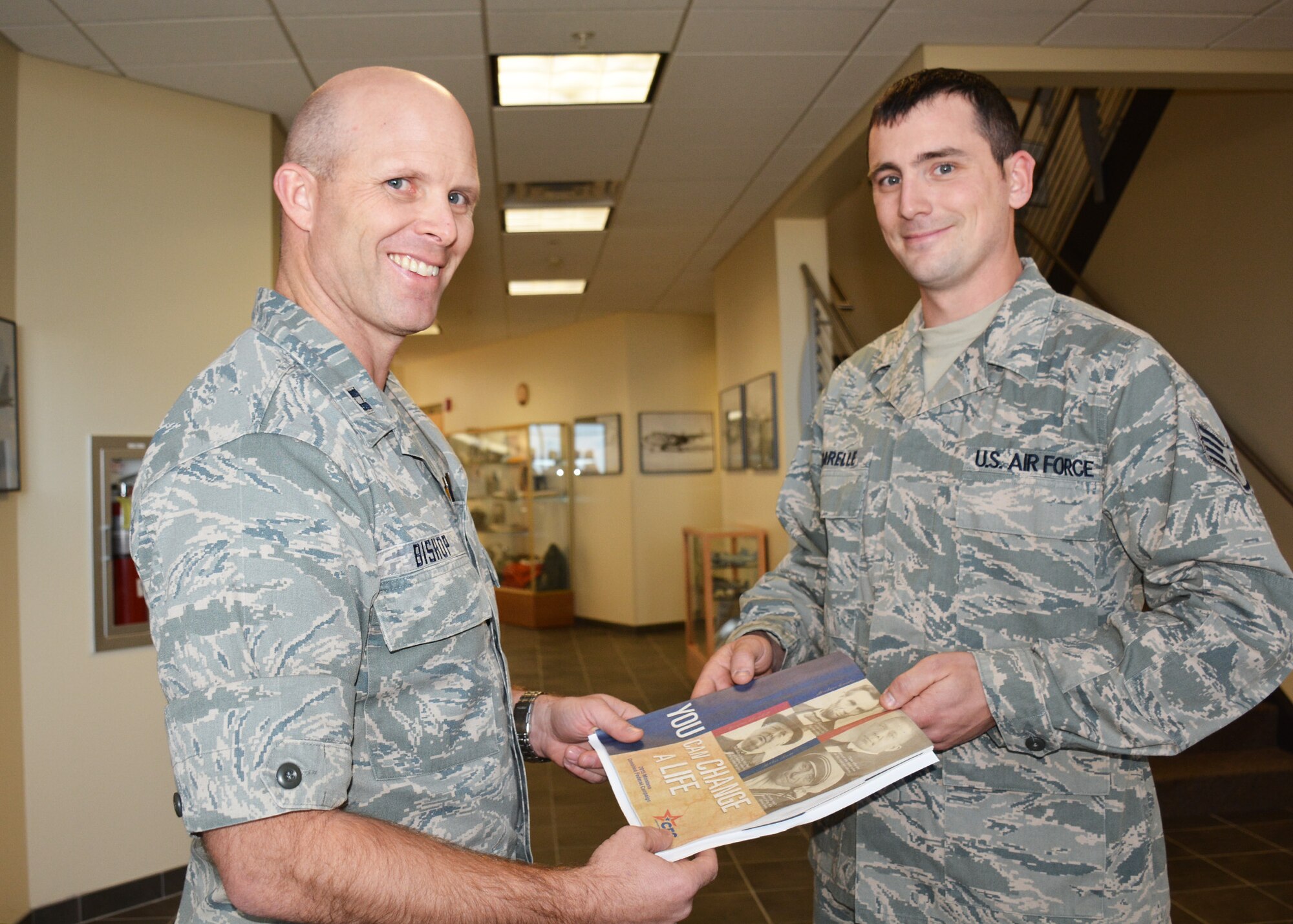 120th Airlift Wing Combined Federal Campaign Officer Capt. Clint Bishop presents Staff Sgt. Nicholas Figarelle with a 2015 Combined Federal Campaign booklet. The local campaign to collect charitable contributions began Nov. 6 and will run through Dec. 6, 2015. (U.S. Air National Guard photo by Senior Master Sgt. Eric Peterson)