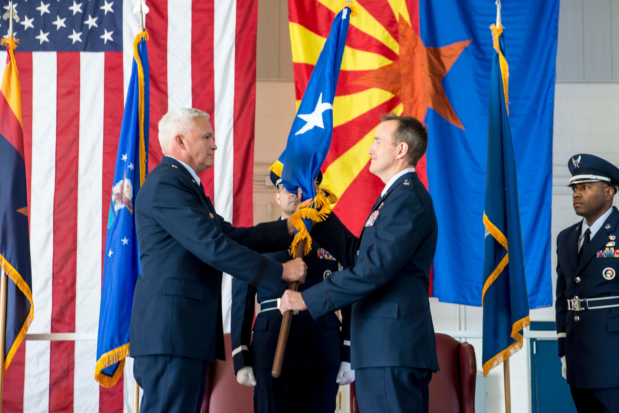 TUCSON, Ariz. -- The commander of the Arizona Air National Guard, Brig. Gen. Edward P. Maxwell, left, symbolically recognizes the presence of a new general by passing the customary one-star brigadier general flag to newly-promoted Brig. Gen. Howard P. Purcell, 162nd Wing Commander. “No matter what my rank, being a part of your team is the job of a lifetime,” said Purcell. “I am extremely proud to be your commander and can’t thank you enough.” (U.S. Air National Guard photo by Tech. Sgt. Hollie A. Hansen /Released)