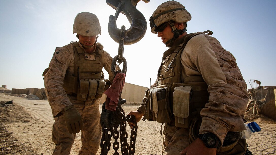 U.S. Marine Sgt. Greggory Sgarlata, an engineer equipment operator with Engineer Company, Combat Logistics Battalion 1, and Sgt. Zackary Cleveland, a motor transport operator with Marine Wing Support Squadron 372, both currently deployed in support of Special Purpose Marine Air Ground Task Force-Crisis Response-Central Command 16.1, prepare the hook block of a MAC-50 Crane to move Alaskan walls at Al Taqaddum Air Base, Iraq, Oct. 25, 2015. The 12-ton T-walls are placed around key structures to provide protection from shrapnel. 