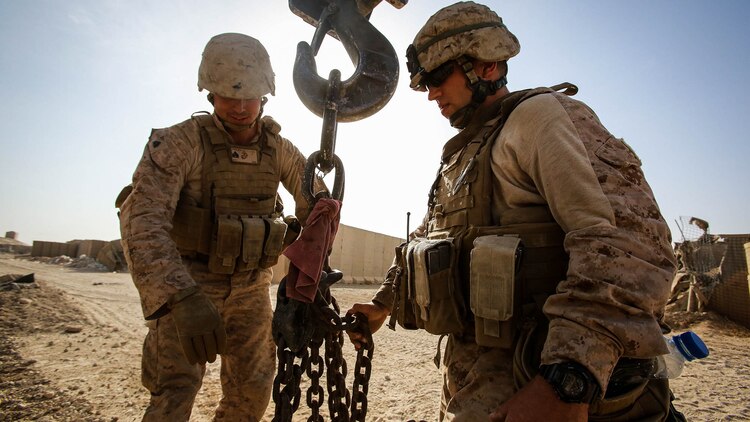 U.S. Marine Sgt. Greggory Sgarlata, an engineer equipment operator with Engineer Company, Combat Logistics Battalion 1, and Sgt. Zackary Cleveland, a motor transport operator with Marine Wing Support Squadron 372, both currently deployed in support of Special Purpose Marine Air Ground Task Force-Crisis Response-Central Command 16.1, prepare the hook block of a MAC-50 Crane to move Alaskan walls at Al Taqaddum Air Base, Iraq, Oct. 25, 2015. The 12-ton T-walls are placed around key structures to provide protection from shrapnel. 