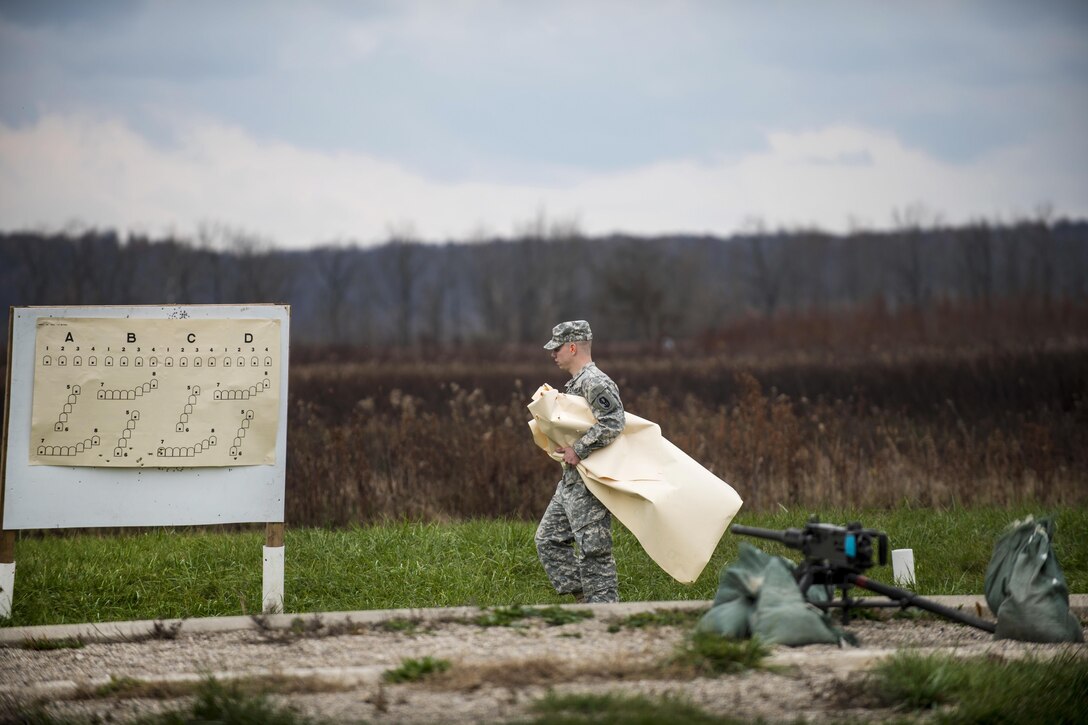 A soldier rips down paper targets at a range for military police soldiers as part of an M2 Browning .50-caliber machine gun familiarization at Camp Atterbury, Ind., Nov. 5, 2015. The soldier is an Army Reservist assigned to the 95th Infantry Division's 1st Battalion, 330th Infantry Regiment. More than 550 Army Reserve soldiers spent three days during a field training exercise that incorporated eight weapons systems. U.S. Army photo by Master Sgt. Michel Sauret