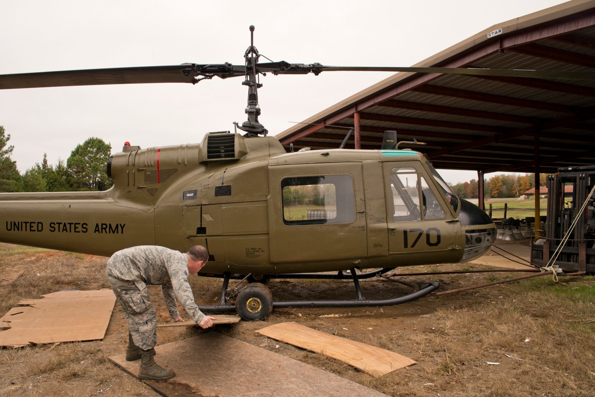 U.S. Air Force Staff Sgt. Brandon Thelen, sheet metal craftsman, 913th Maintenance Squadron, places plywood under the transport wheels of a Bell UH-1C Iroquois (Huey) helicopter at the city recycling center in Jacksonville, Ark., Nov. 3, 2015. The newly restored Vietnam era Huey was being moved through a muddy area to a dry staging area so it could be returned to the Jacksonville Museum of Military History the next day. (U.S. Air Force photo by Master Sgt. Jeff Walston/Released)