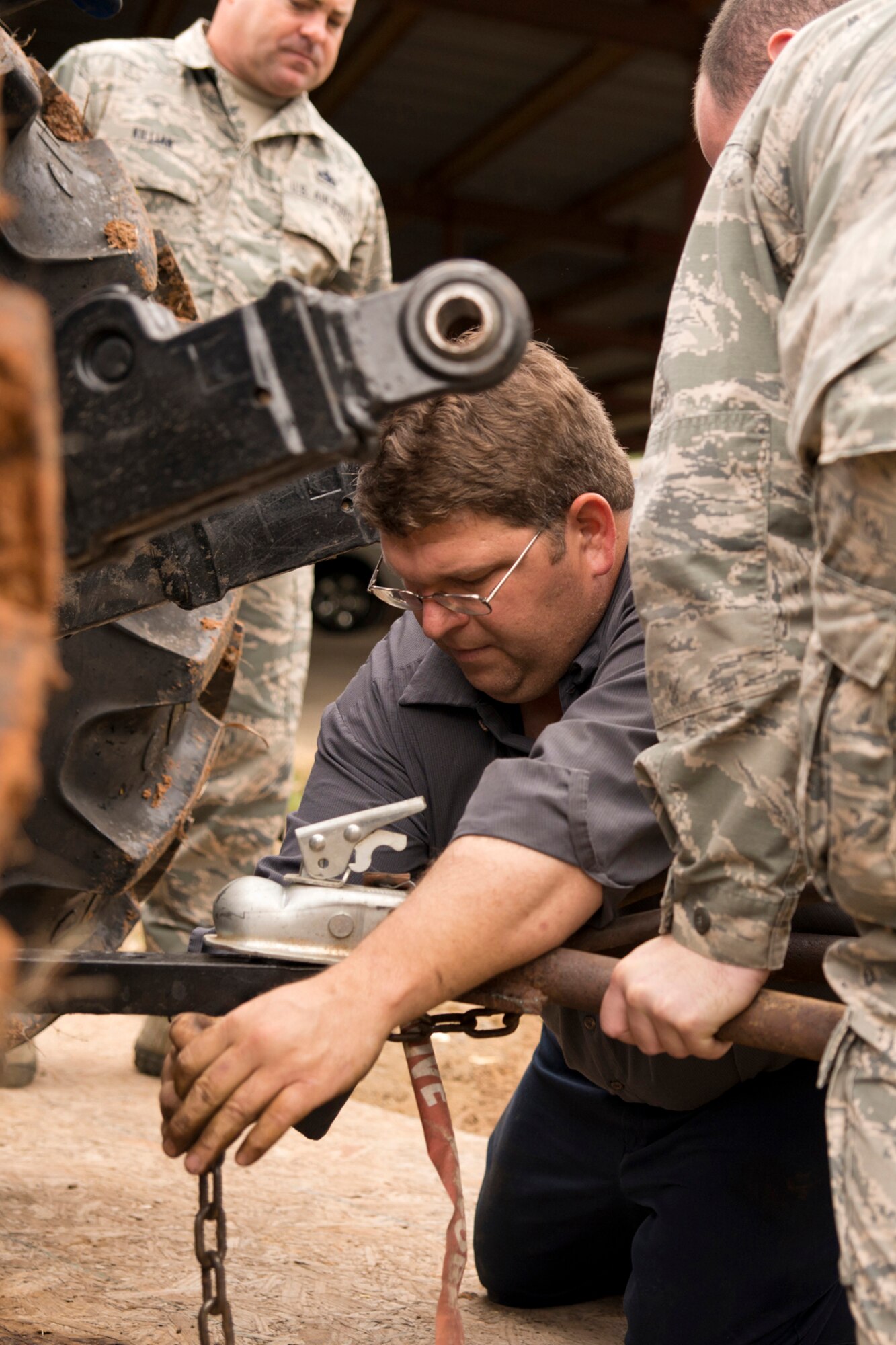 Randy Watkins, sanitation superintendent, City of Jacksonville, Ark., chains a towing hitch to a tractor, after a forklift got stuck in the mud trying to move a newly restored Vietnam era Bell UH-1C Iroquois helicopter to a staging area at the city recycling center in Jacksonville, Ark., Nov. 3, 2015. The helicopter was returned to the Jacksonville Museum of Military History the next day. (U.S. Air Force photo by Master Sgt. Jeff Walston/Released)