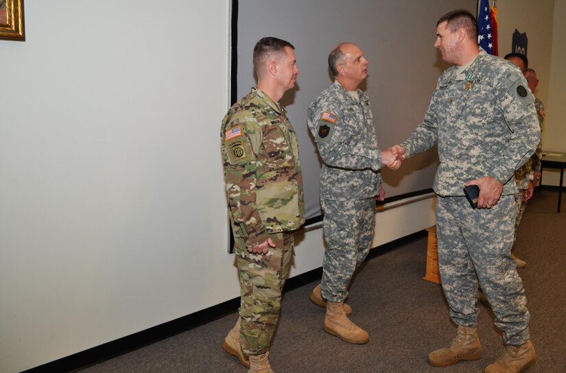 Brig. Gen. Jason Walrath, commander 100th Training Division, looks on as Brig. Gen. Brig. Gen. Thomas P. Evans, deputy commander 80th Training Command, congratulates the 80th TC Instructor Of the Year in the officer category, Maj. David Porter, 102d Training Division, during an award ceremony at Fort Knox, Ky., Nov. 7, 2015.