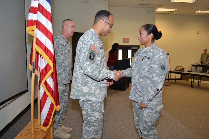 Command Sgt. Maj. Jeffrey Darlington, the 80th Training Command senior noncommissioned officer, looks on as Maj. Gen. A.C. Roper, commander 80th TC, congratulates Staff Sgt. Jadrian Whitfield, 100th Training Division, after Roper awarded her the Army Commendation Medal for winning the 80th TC Instructor Of the Year competition in the noncommissioned officer category during an award ceremony at Fort Knox, Ky., Nov. 7, 2015.