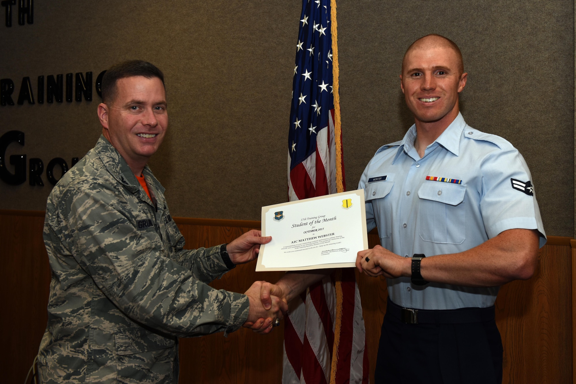 U.S. Air Force Col. Michael Grunwald Jr., 17th Training Group Commander, presents the 312th Training Squadron Student of the Month award for October 2015 to Airman 1st Class Matthew Webster in the Brandenburg Hall on Goodfellow Air Force Base, Texas, Nov. 6, 2015. (U.S. Air Force photo by Airman Chase Sousa/Released)