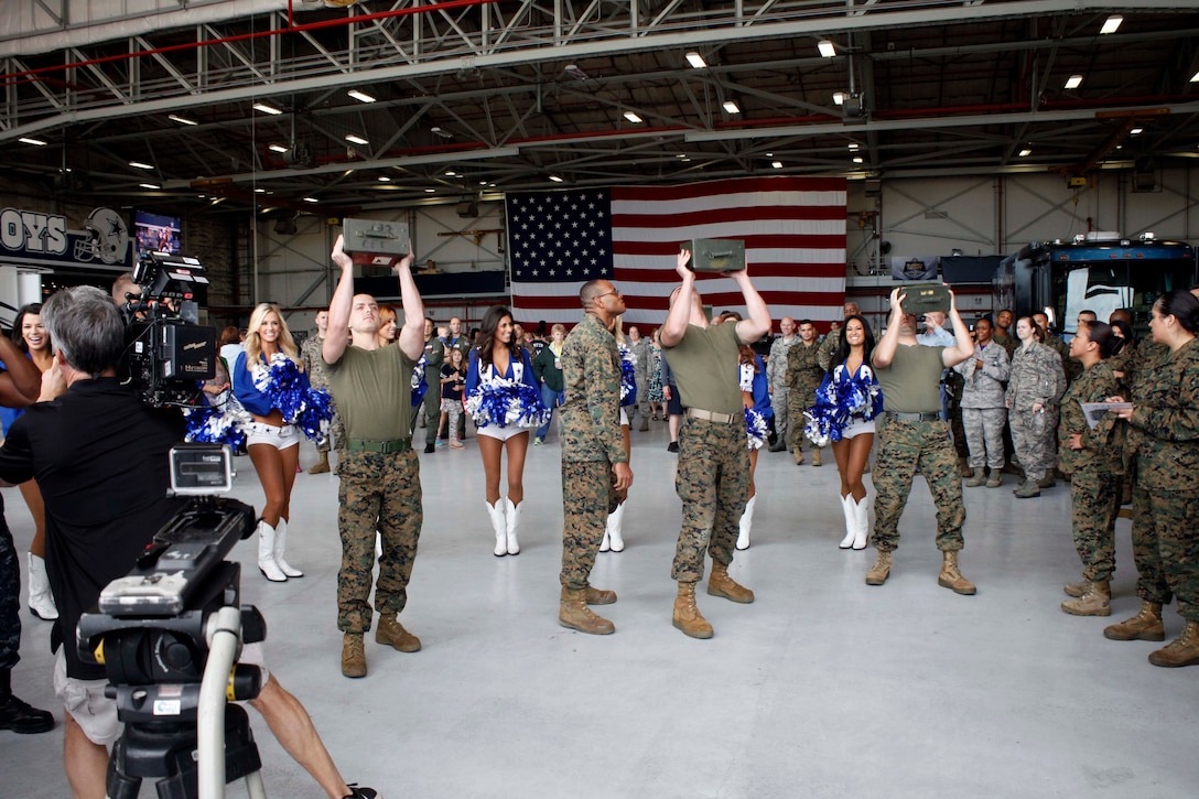 Marines stationed at Naval Air Station Joint Reserve Base Fort Worth are cheered on by Dallas Cowboys cheerleaders during an ammo can lift competition. The competition was part of the Dallas Cowboys Military Appreciation event held to show the team’s support to service members and their families Nov. 6, 2015.