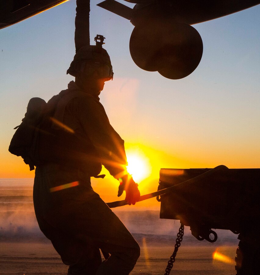 U.S. Marine Lance Cpl. Dustin Mason, a landing support specialist, with the Landing Support Detachment, 26th Marine Expeditionary Unit embarked aboard the amphibious transport dock ship USS Arlington (LPD 24), holds the sling connecting the M105 trailer to a CH-53E Super Stallion with Marine Medium Tiltrotor Squadron (VMM) 162 (Reinforced), 26th MEU, embarked on the USS Arlington, hovering overhead during an external lift training exercise at Pinheiro Da Cruz, Praia Da Raposa Beach, Portugal, Oct. 22, 2015, during Trident Juncture 15. Trident Juncture is a NATO-led exercise designed to certify NATO response forces and develop interoperability among participating NATO and partner nations. 