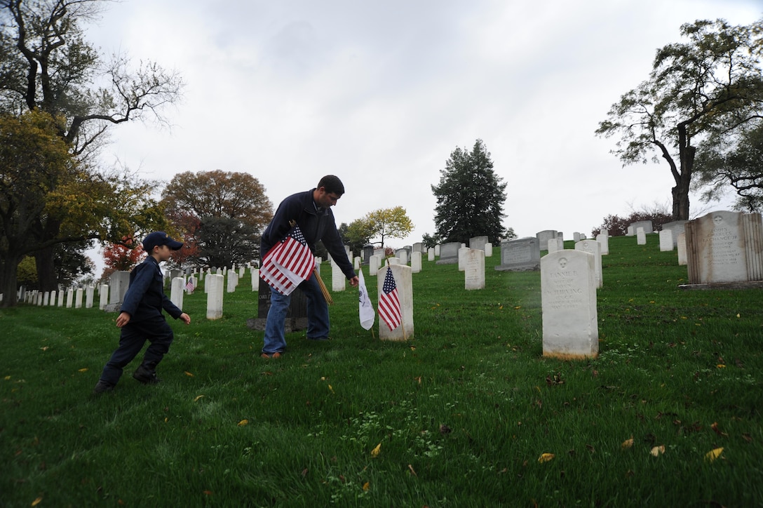 A Coast Guard family takes part in the Coast Guard's Flags Across America event at Arlington National Cemetery in Arlington, Va., Nov. 7, 2015. During the event, Coast Guard members, their families, friends, and former members placed Coast Guard flags and national ensigns on the graves of Coast Guardsmen ahead of Veterans Day. U.S. Coast Guard photo by Petty Officer 3rd Class Lisa A. Ferdinando