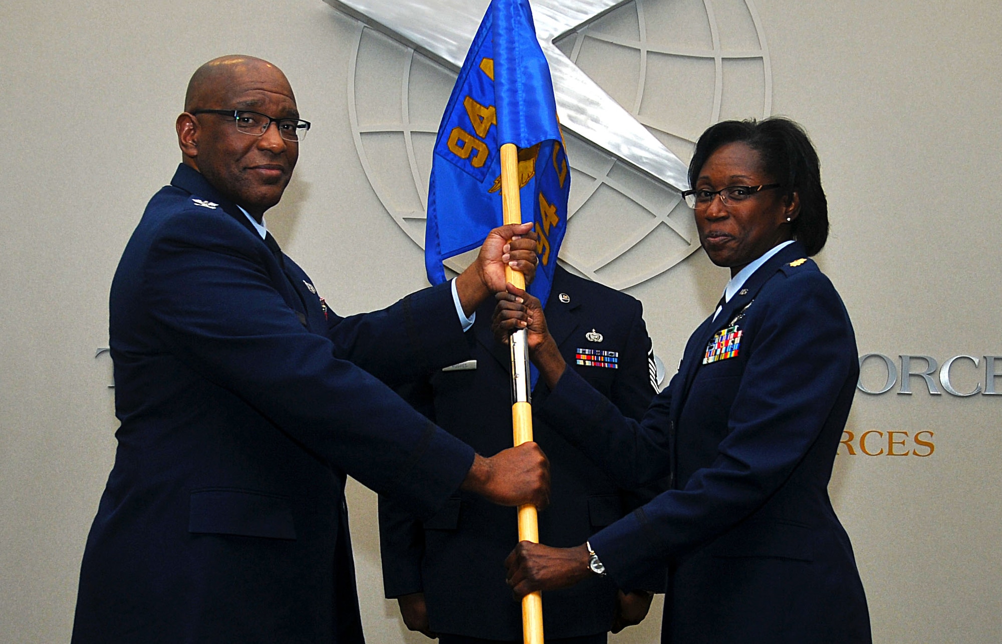 Maj. Andrea M. Walthour receives the 94th Communications Squadron flag from Col. Marshall S. Irvin, Jr., 94th Mission Support Group commander, in the 22nd Air Force Media Center on Nov. 7, 2015, and thereby assumes command of the 94th Communications Squadron at Dobbins Air Reserve Base, Ga. Walthour previously served as the Individual Mobilization Augmentee to the 78th Force Support Squadron Director, Robins Air Force Base, Ga. (U.S. Air Force photo/ Senior Airman Andrew J. Park)