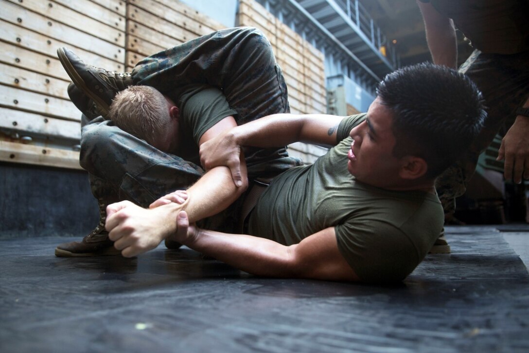GULF OF ADEN  (Oct. 17, 2015) U.S Marine Lance Cpl Giovanni Carrera, right, fights for an arm bar on Cpl. Shawn Obrien during the combat conditioning portion of a Marine Corps Martial Arts Program black belt course aboard the USS Rushmore (LSD 47). Obrien is an amphibious assault vehicle crew chief and Carrera is an AAV crewman, both with Kilo Company, Battalion Landing Team 3rd Battalion, 1st Marine Regiment, 15th MEU. In addition enhancing hand-to-hand combat skills, MCMAP sharpens the decision making and mental toughness of the Marines by instilling a warrior ethos. (U.S. Marine Corps photo by Sgt. Emmanuel Ramos/Released)