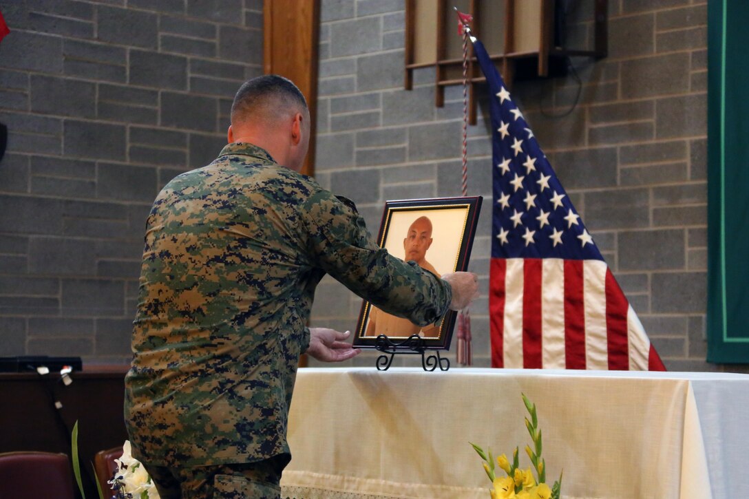 A Marine places a portrait of Staff Sgt. Denver Sugano on an altar during a memorial service at Marine Corps Air Station New River, N.C., Nov. 4, 2015.  Sugano faithfully served in the Marine Corps for 13 years, primarily serving as a flight equipment technician and a Marine recruiter. Sugano participated in three Unit Deployment Programs, assisted with Hurricane Sandy relief efforts and deployed in support of the 26th Marine Expeditionary Unit. Family, friends and fellow Marines remember Sugano for his dedication to his beloved Corps and his family.  (U.S. Marine Corps photo by Cpl. N.W. Huertas/Released)