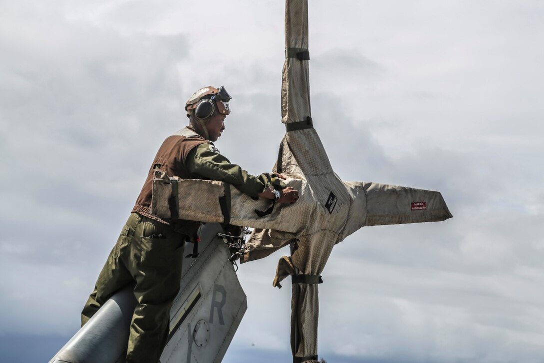 INDIAN OCEAN (Nov. 6, 2015) U.S. Marine Cpl. Joseph Jones places rain gear on the tail rotor of an AH-1Z Viper aboard the USS Anchorage (LPD 23). Jones is a flightline mechanic with Marine Medium Tiltrotor Squadron 161 (Reinforced), 15th Marine Expeditionary Unit. The 15th MEU is currently deployed in the Indo-Asia-Pacific region to promote regional stability and security in the U.S. 7th Fleet area of operations. (U.S. Marine Corps photo by Sgt. Steve H. Lopez/Released)