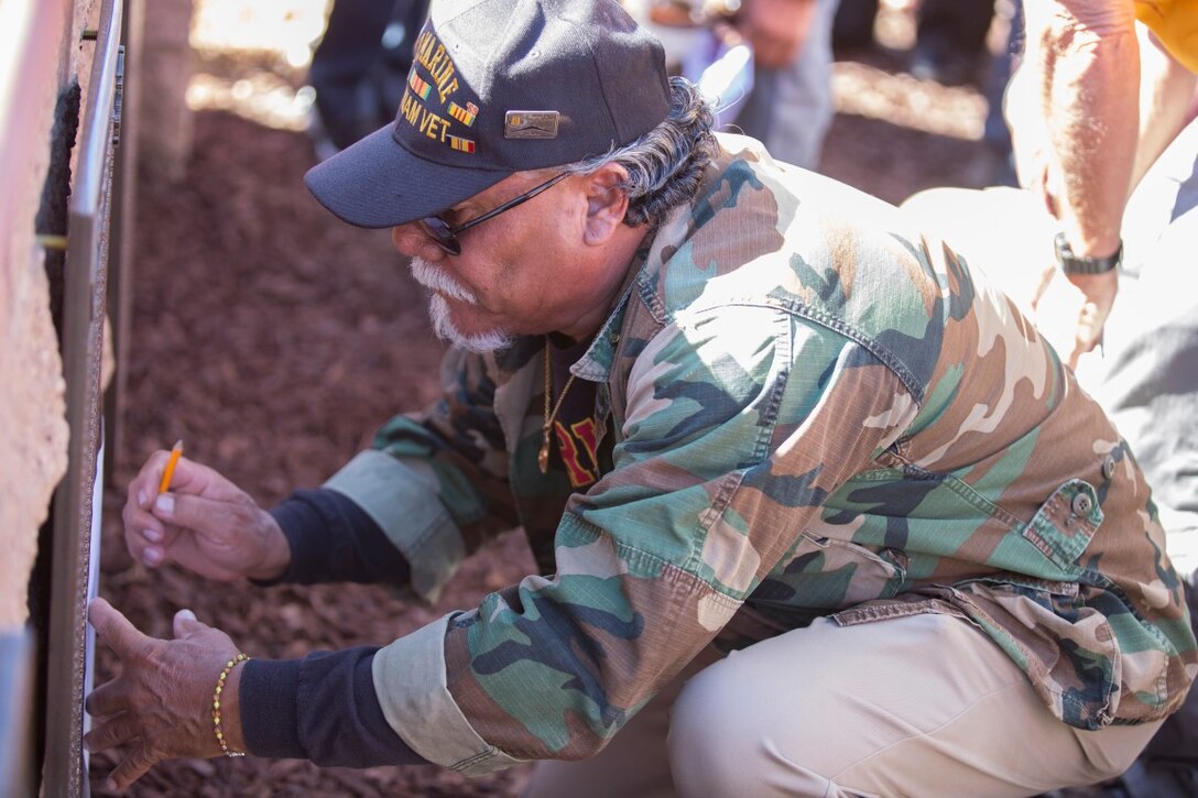 Lucio Lopez, a Vietnam veteran of 2nd Battalion, 1st Marine Regiment, sketches the plaque of a fallen member of his company Nov. 6, 2015, aboard Marine Corps Base Camp Pendleton, Calif., during a ceremony honoring members of the regiment who gave their lives during the Vietnam War. During the Ceremony, plaques bearing the names of the fallen were dedicated in their honor at the Camp Horno Memorial Garden. (U.S. Marine Corps photo by Lance Cpl. Alvin Pujols/Released)
