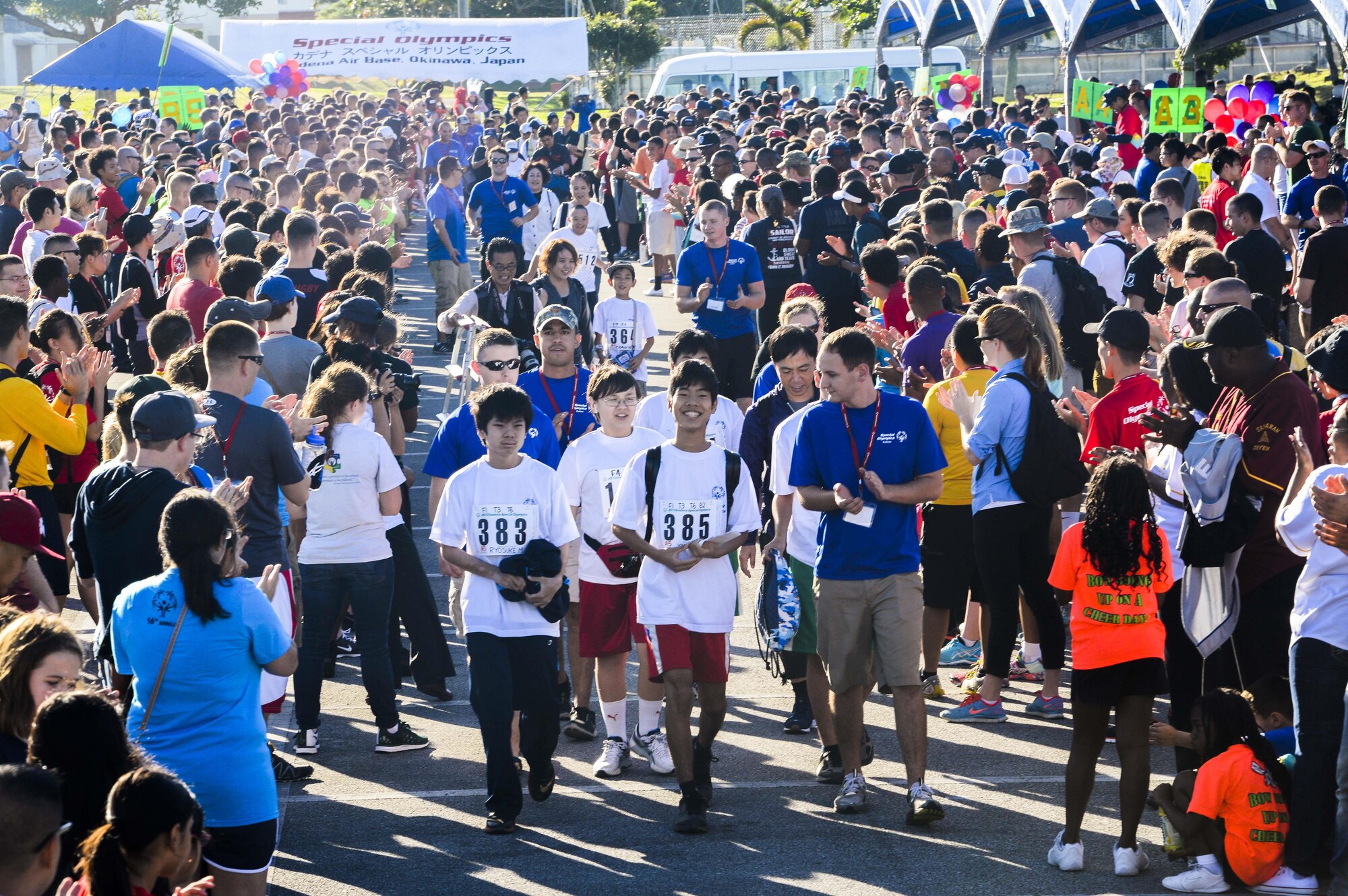 Hundreds of volunteers and spectators of the Kadena Special Olympics form a human pathway to greet and cheer on arriving athletes as they are shuttled to the Risner Fitness Center Sports Complex Nov. 7, 2015, at Kadena Air Base, Japan. Thousands of spectators from Japan and the U.S. came out to support approximately 880 athletes and artists participating in the 16th annual KSO games and art show. (U.S. Air Force photo by Senior Airman John Linzmeier/Released) 