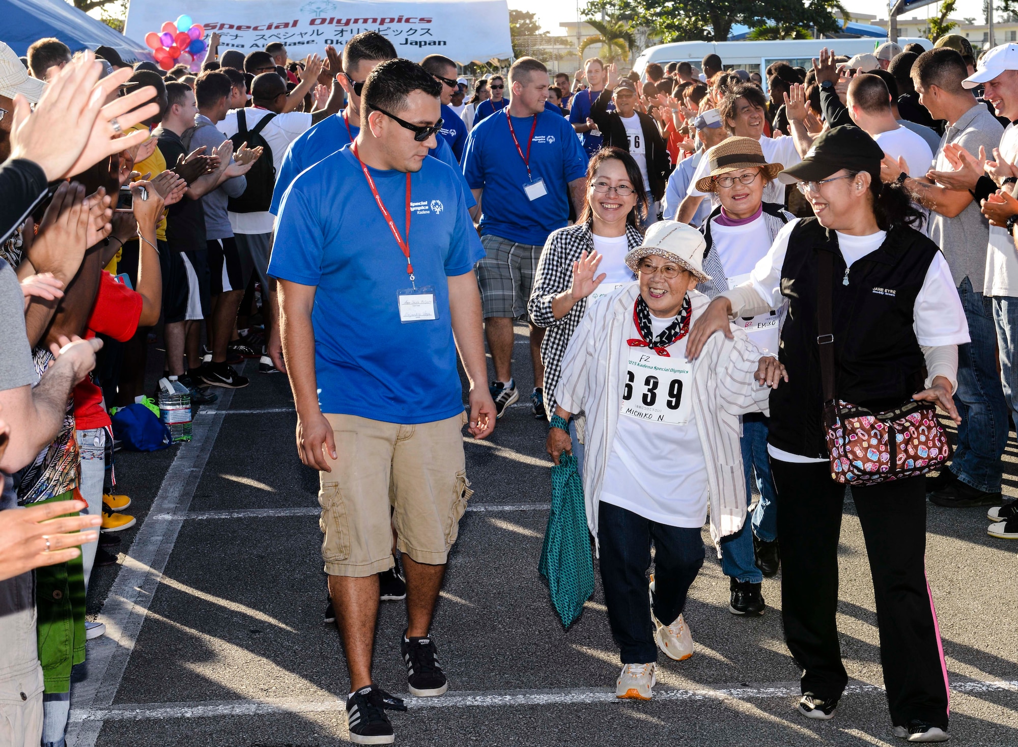 Michiko Nakasone and other Kadena Special Olympics athletes are cheered and applauded by a crowd as they arrive at the Risner Fitness Center Sports Complex Nov. 7, 2015, at Kadena Air Base, Japan. Approximately 1,700 volunteers helped nearly 900 athletes arrive to their events and compete in the largest overseas Special Olympics event in the world. (U.S. Air Force photo by Senior Airman John Linzmeier/Released) 