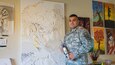 Sgt. 1st Class Pedro Rios, 311th Theater Signal Command, Costa Mesa, Calif., stands in front of a work of art in progress. Rios has created a unique body of work by blending trees with figures over built up texture at his home art studio.