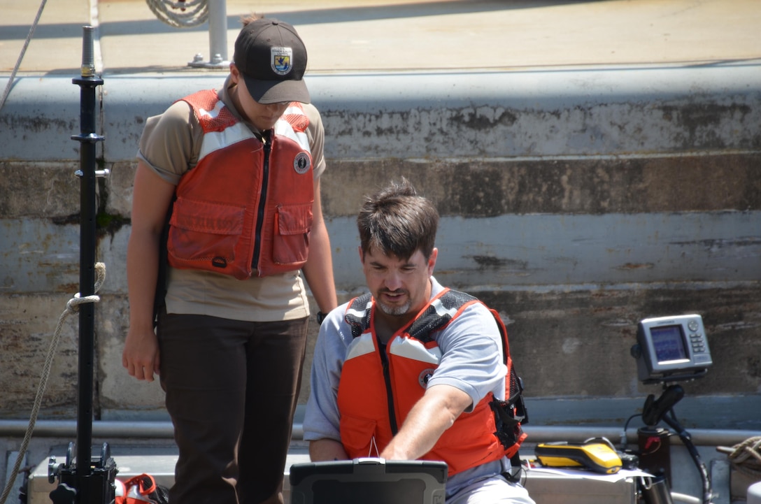 Elliot Stefanik, sitting, fish biologist, explains to Jenna Merry, U.S Fish and Wildlife Service student, how the hydro-acoustic camera will help researches better understand fish behavior within the Mississippi River.