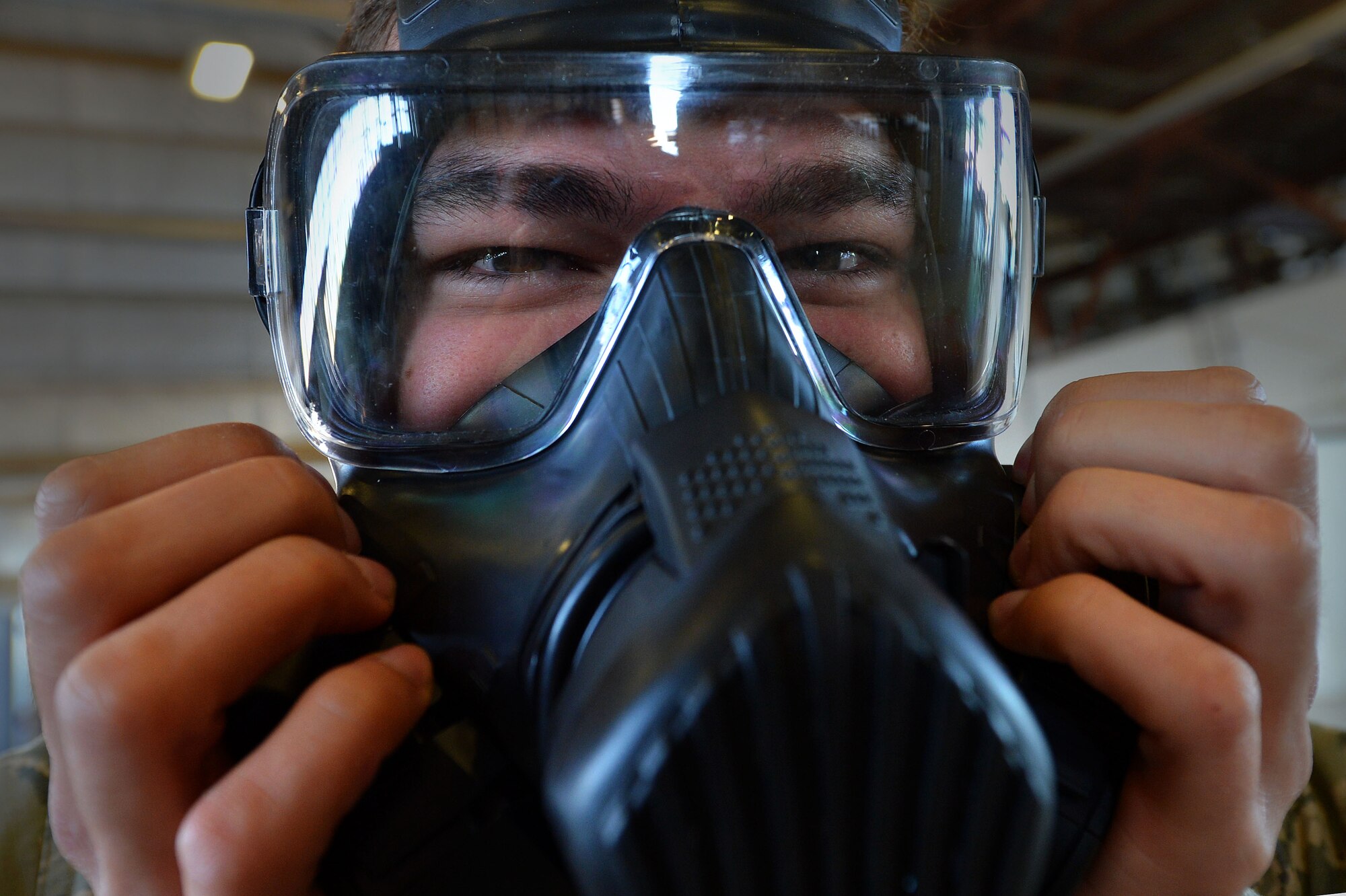 U.S. Air Force Airman 1st Class Kyle Denzine, 20th Operations Support Squadron aircrew flight equipment specialist, checks the seal of his gas mask at Shaw Air Force Base, S.C., Oct. 23, 2015. Denzine along with other AFE Airmen practiced the actions they would take in the event a pilot needs to be decontaminated upon his return to base. (U.S. Air Force photo by Senior Airman Michael Cossaboom)