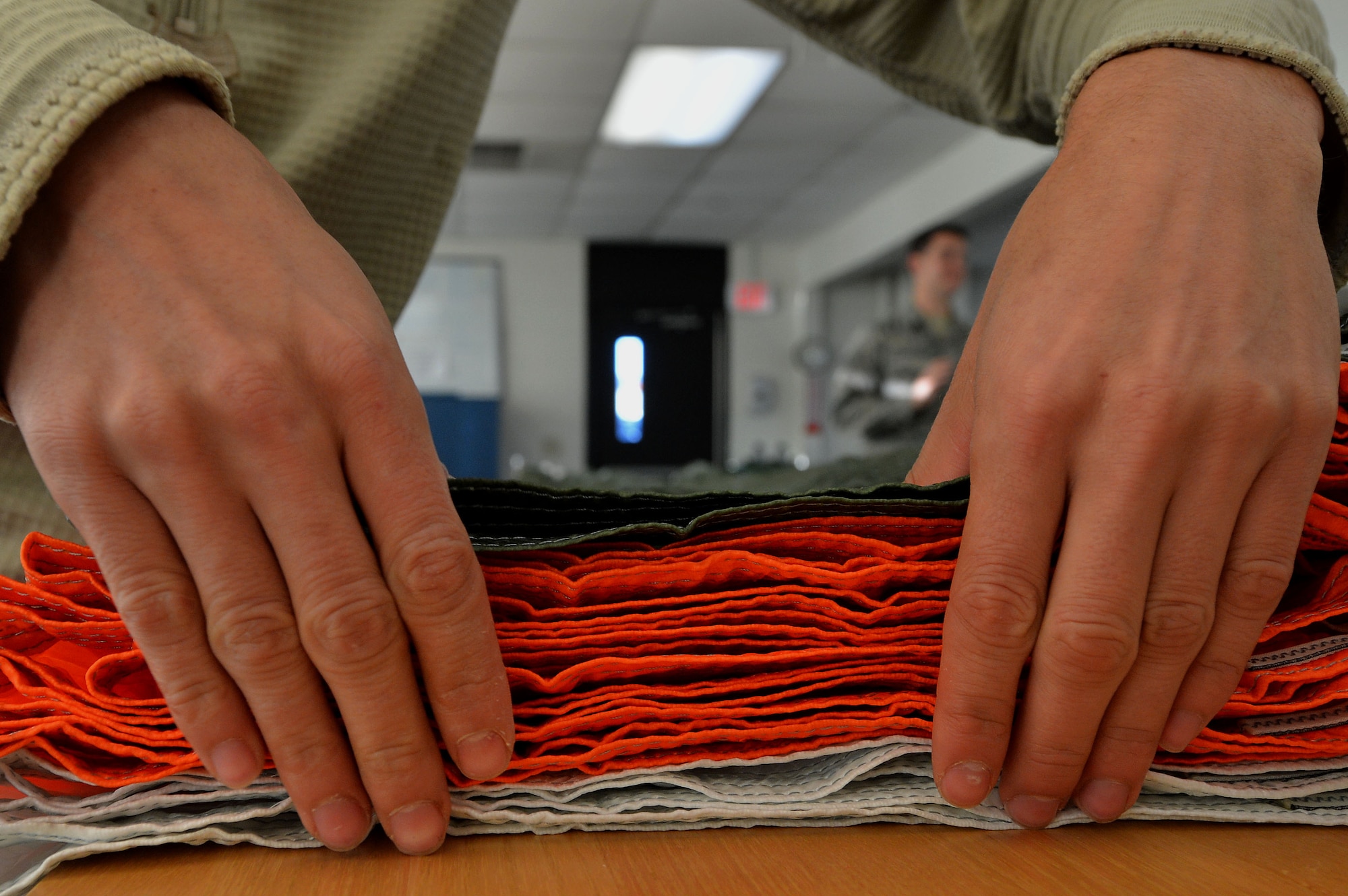 U.S. Air Force Airman 1st Class Kyle Denzine, 20th Operations Support Squadron aircrew flight equipment specialist, smooths out a parachute  at Shaw Air Force Base, S.C., Oct. 20, 2015. Before the parachute gets packed, AFE Airmen must inspect it to ensure it is free of tears and debris. (U.S. Air Force photo by Senior Airman Michael Cossaboom)