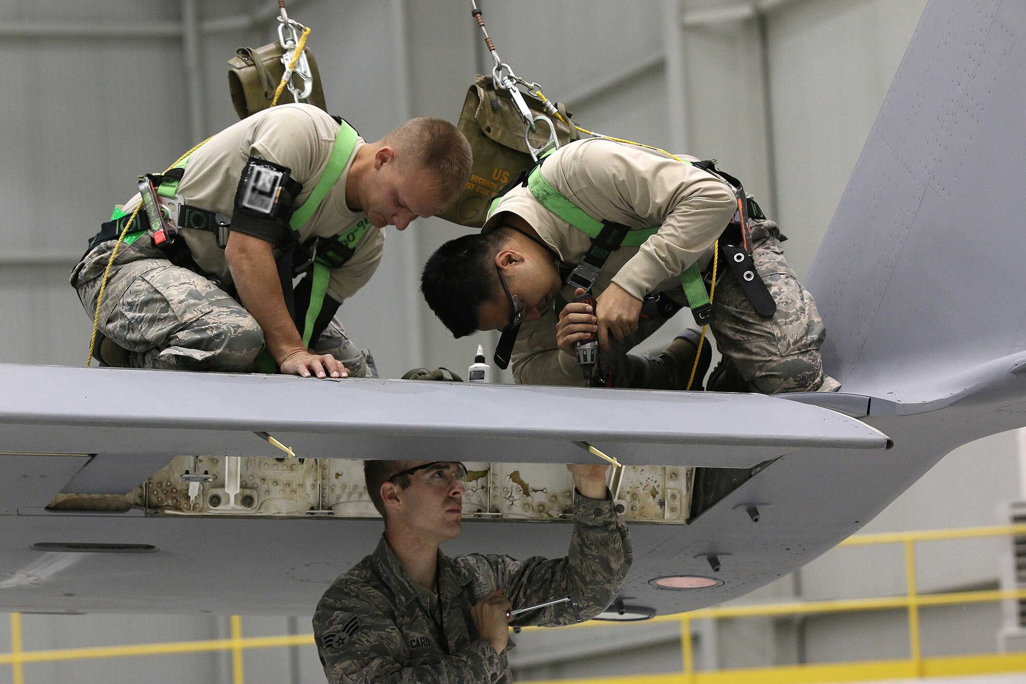 WRIGHT-PATTERSON AIR FORCE BASE, Ohio – Senior Airmen Matthew Card (bottom), Michael Kessinger (top left) and  John Tapia (top right),  all 445th Aircraft Maintenance Squadron crew chiefs, complete structural repairs on a flight control panel of a C-17 Globemaster III. (U.S. Air Force photo/Tech. Sgt. Patrick O’Reilly)