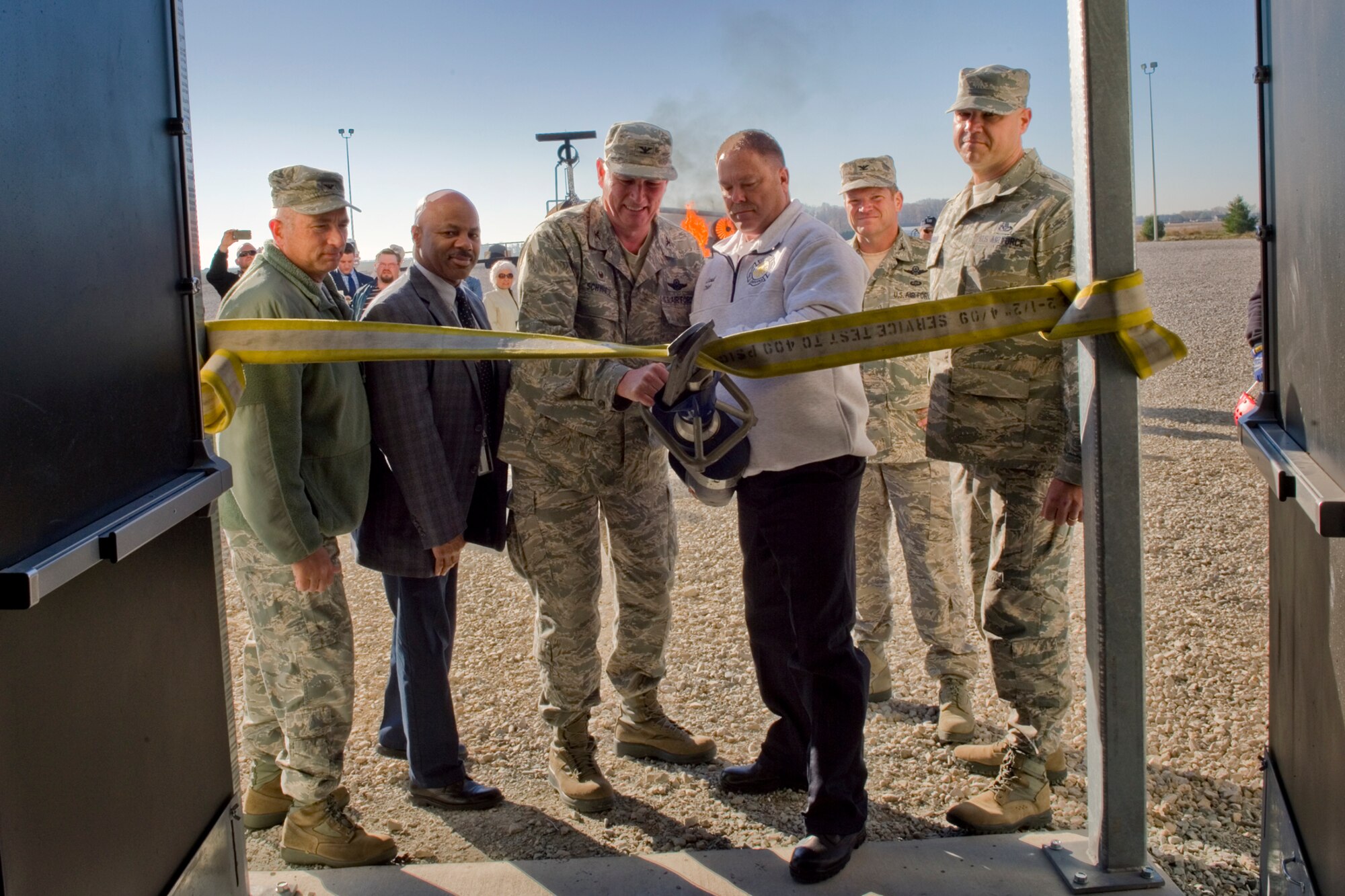 Col. Doug Schwartz, 434th Air Refueling Wing commander, and John Ireland, Grissom Fire Department fire chief, use jaws of life to cut a fire hose while (from left to right) Col. Scott Russell, 434th Mission Support Group commander, Kevin Jefferson, Louisville Army Corps of Engineers representative, Col. Hiram P. Gates, 434th ARW vice commander, and Chief Master Sgt. Rob Herman, 434th ARW command chief, observe during a ribbon cutting ceremony at Grissom Air Reserve Base, Ind., Nov. 9, 2015. The new facility will help provide firefighters with mandated training requirements. (U.S. Air Force photo/Tech. Sgt. Benjamin Mota)