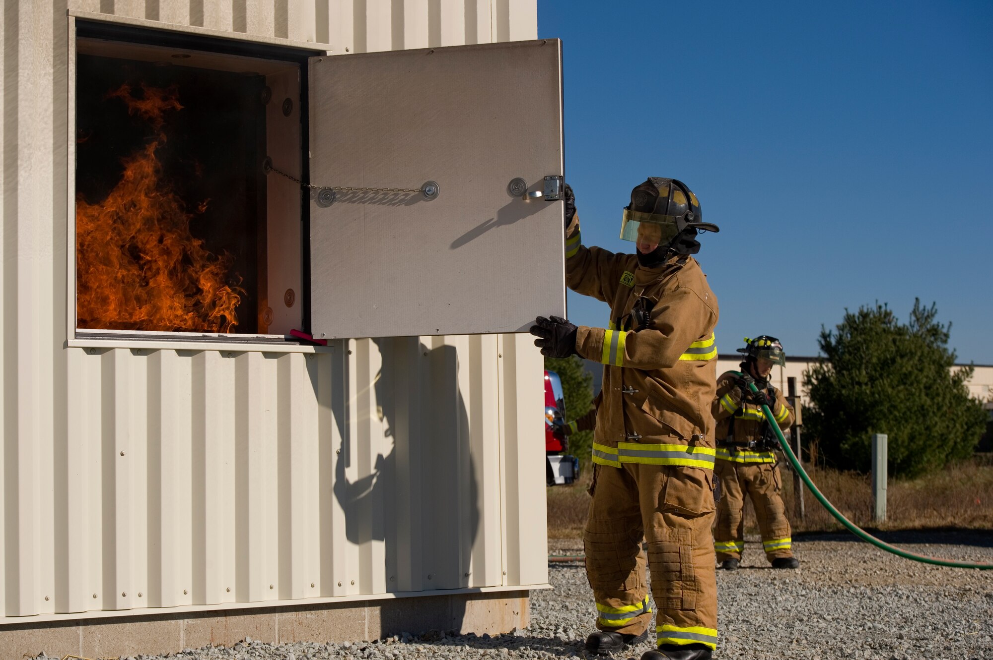 Mark Ashbaugh, Grissom Fire Department firefighter, opens a hatch to Grissom's recently renovated smoke house, allowing oxygen to feed a fire during a ribbon cutting ceremony at Grissom Air Reserve Base, Ind., Nov. 9, 2015. Grissom's new fire training facility will help provide firefighters with mandated training requirements. (U.S. Air Force photo/Tech. Sgt. Benjamin Mota)