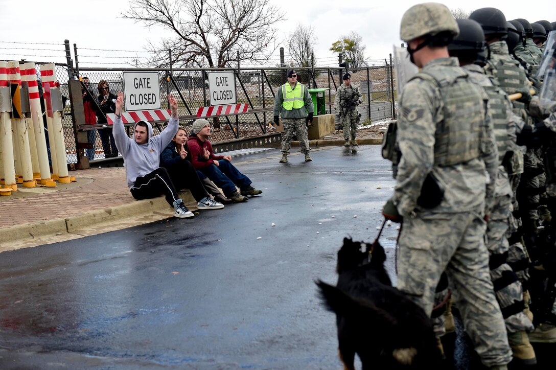 Members of the 460th Security Forces Squadron observe group of mock protesters during the Panther Lightning exercise Nov. 5, 2015, at the 6th Avenue Gate on Buckley Air Force Base, Colo. The protest was added as a local scenario to the U.S. Strategic Command exercise, Global Lightning, which bases participated to increase preparedness and the ability to respond to a threat. (U.S. Air Force photo by Senior Airman Phillip Houk/Released)